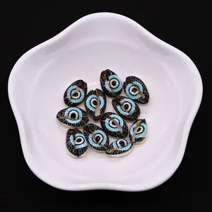 Macro detail of natural conch shell beads with blue evil eye pattern in white dish