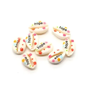Macro detail of cowrie shell beads with Hope lettering and colorful floral patterns