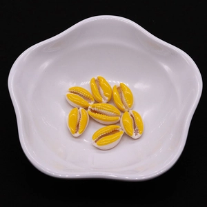 Macro view of 7 yellow shell beads for DIY jewelry making in a white wavy bowl