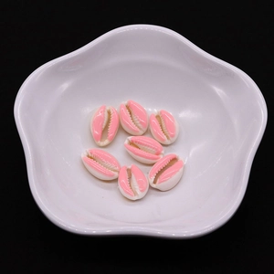 Detailed view of pink and white shell-shaped resin beads in a white ceramic petal bowl