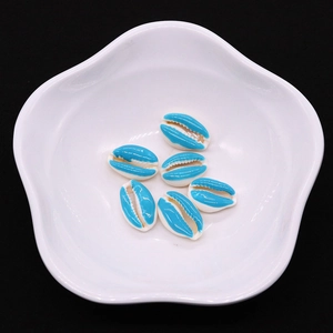 Close-up of sky blue candy-colored sea shell beads in a white ceramic petal dish