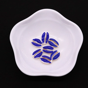 Close-up of 9x19mm deep blue enameled conch shells in a white ceramic bowl