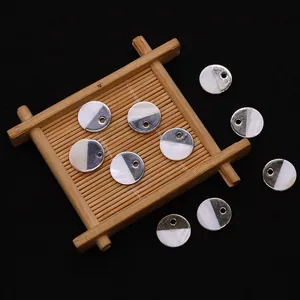 Détail de pendentifs ronds en nacre et métal argenté sur un plateau en bambou pour bijoux
