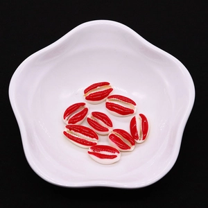 Macro detail of red enamel cowrie shell beads for DIY jewelry making in a white bowl