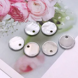 Gros plan de breloques rondes en nacre de 15 mm avec bordure en métal argenté pour bijoux DIY