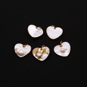 Dettaglio di ciondoli in madreperla a forma di cuore con bordo placcato oro su sfondo nero
