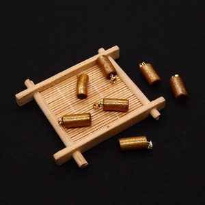 Detail view of six 10x22mm golden synthetic coral cylinder pendants on a bamboo tray