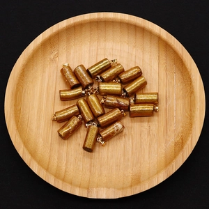 Macro detail of 10x22mm gold coral cylinder charms with sparkling texture for DIY jewelry