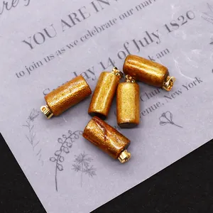 Macro detail of 5 cylindrical gold-plated synthetic coral pendants with a textured finish