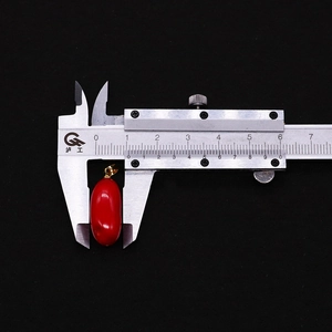 Misura dettagliata del ciondolo in corallo rosso a forma di riso con un calibro digitale
