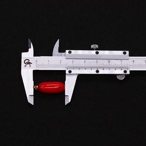 Dettaglio del ciondolo corallo rosso a forma di riso misurato con calibro di 25 mm