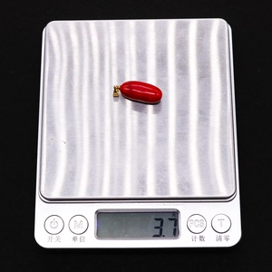 Pendente in corallo sintetico rosso 10x25mm su bilancia con peso di 3,7g visualizzato