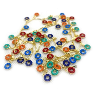 Primer plano de dijes redondos de esmalte de colores y cadena dorada para joyas DIY