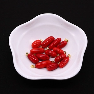 Pendenti in corallo sintetico rosso con ganci dorati in una ciotola di ceramica bianca