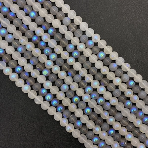 Macro detail of natural moonstone round beads showing blue and green flash on black background