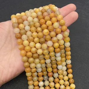 Makro-Detail von runden Natur-Gelbtopas-Perlen für die Schmuckherstellung in der Hand