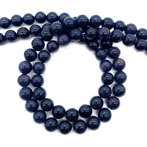 Détail macro de perles rondes en pierre de sable bleu scintillant sur fond blanc