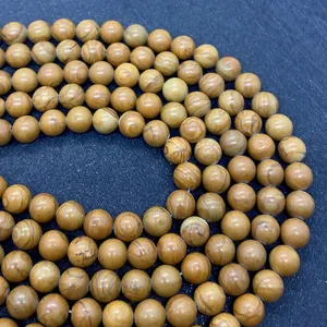 Dettaglio di perle in pietra naturale venata di legno lucido per la creazione di gioielli