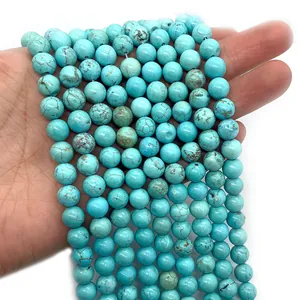 Gepolijste turquoise ronde kralen met bruine patronen in de hand voor het maken van sieraden