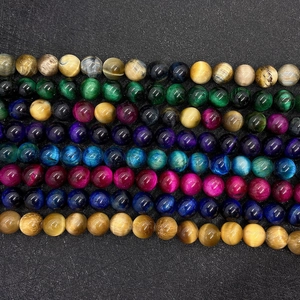 Macro view of multi-color tiger eye stone beads with natural chatoyant effect on black pad