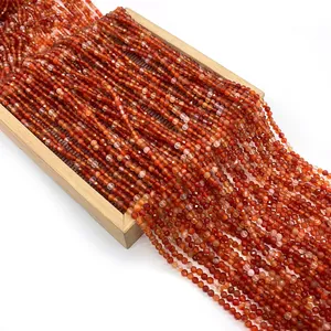 Faceted red agate natural stone beads for DIY jewelry making displayed on a wooden tray