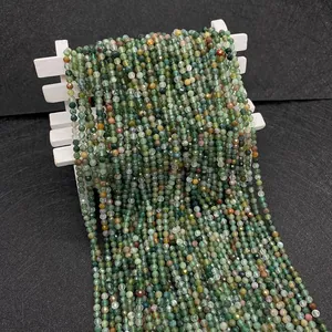 Macro detail of faceted green Indian agate beads draped over a white wooden fence