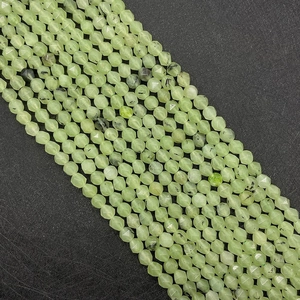 Macro shot of faceted light green prehnite beads with natural black inclusions for DIY jewelry