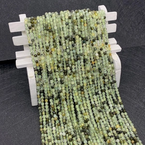 Detail of faceted olive green prehnite beads hanging on a mini white decorative stool