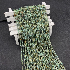 Macro detail of faceted African Turquoise stone beads with natural texture on a mini bench
