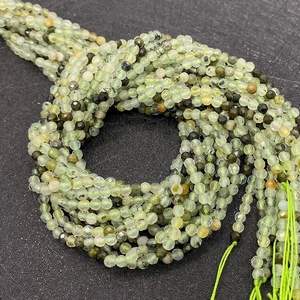 Macro detail of faceted natural prehnite light green stone beads on a dark background