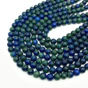 Macro shot of polished round natural phoenix lapis lazuli beads with blue green texture