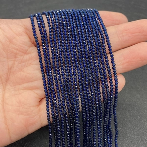 Detalle de cuentas de espinela azul oscuro facetadas de 2-3 mm sostenidas para escala