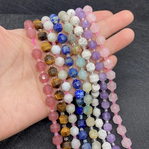 Macro shot of faceted natural gemstone beads held in hand showing texture and luster