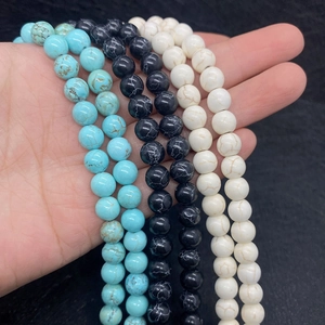 Close-up of blue, black and white marbled turquoise beads held by hand for DIY jewelry