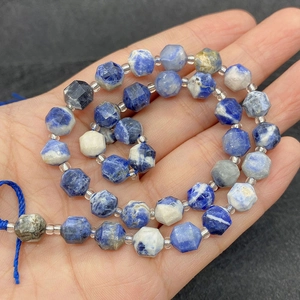 Faceted natural sodalite stone beads in blue and white patterns held in palm
