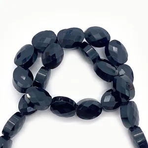Vista macro di perle ovali sfaccettate in pietra naturale nera con superfici lucide