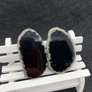 Macro detail of two irregular polished black agate pendants with natural crystal edges