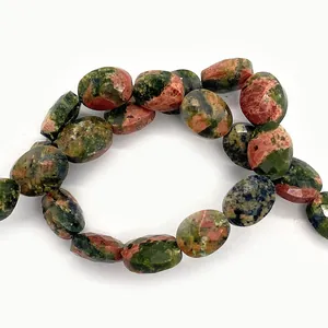 Vista macro di perle ovali sfaccettate in unakite con trame minerali naturali rosse e verdi