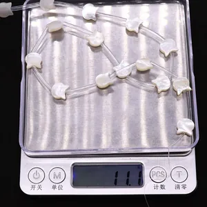Macro di perle in madreperla a forma di gatto da 11,1g su una bilancia digitale per gioielli