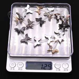 Detail showing natural shell butterfly beads on a scale weighing 12.9 grams total