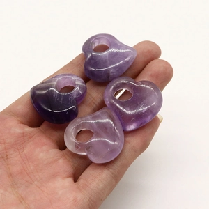 Makroansicht von vier herzförmigen lila Amethyst-Anhängern in der Hand zur Größendarstellung