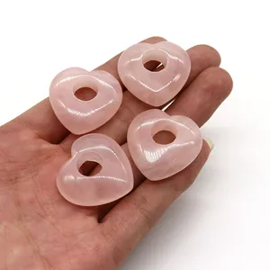 Polierte rosa Quarz Herzperlen in der Hand zur Demonstration der 30mm Größe und Textur