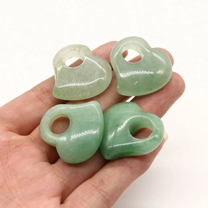 Detailansicht von vier herzförmigen grünen Natursteinen mit Löchern für DIY-Schmuck