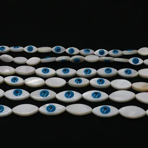 Macro shot of oval shell beads with blue evil eye motifs for handmade jewelry DIY