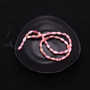 Primer plano de cuentas de concha natural rosa en forma de huso para bisutería DIY