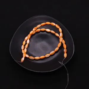 Detalle de cuentas de concha ovaladas naranjas para creación de joyas artesanales