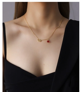 Detail of model wearing a hollow cloud pendant necklace with red bead on black outfit
