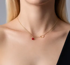 Close-up of golden hollow gourd pendant and red agate bead necklace on model neck