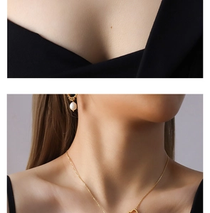 Detail view of heart pendant gold chain and white pearl earrings on female model