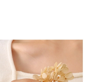 Detailed close-up of a floral cluster brooch with cream petals and gold accents on clothing